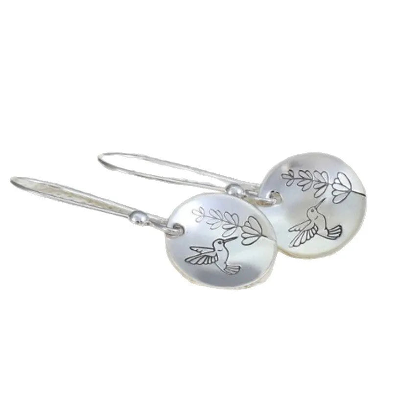 Silver-coloured women's earrings with a glossy round bird and flower design on a white background.