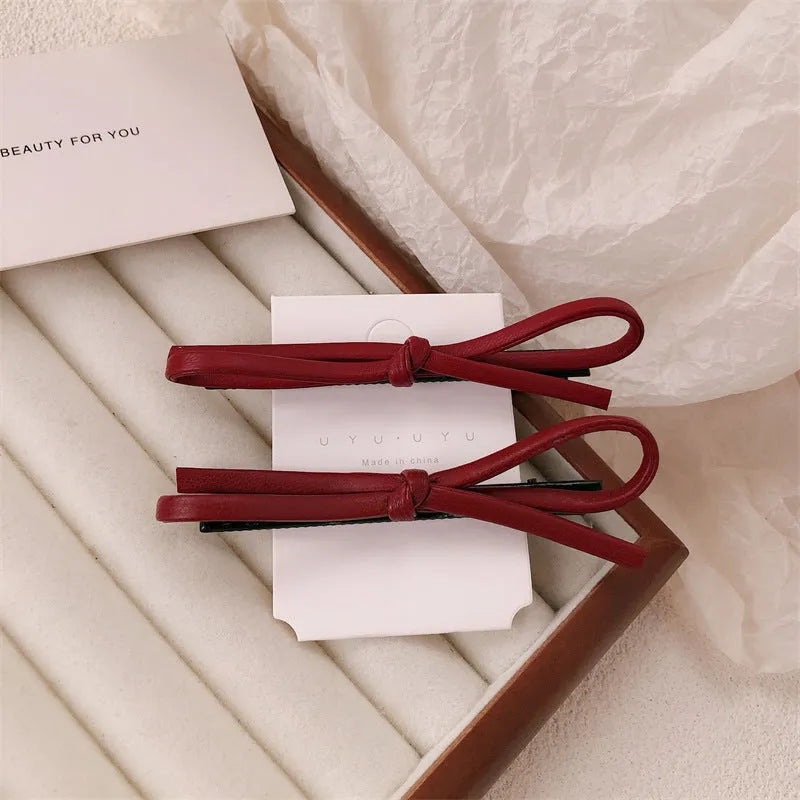 Wine red leather bow barrette hair accessory showing manual craftsmanship and clip mechanism