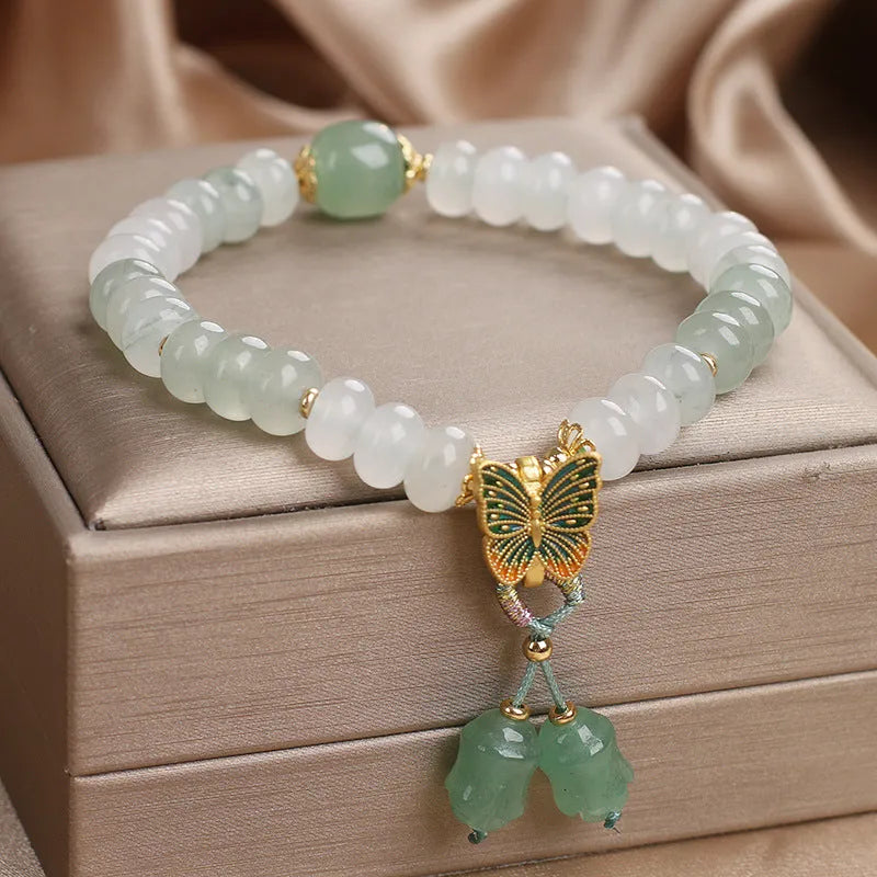Green crystal women's bracelet with abacus beads, a butterfly tassel, pearls, and rhinestones.