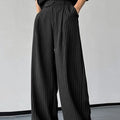 Man wearing black vertical stripe pleated casual trousers.