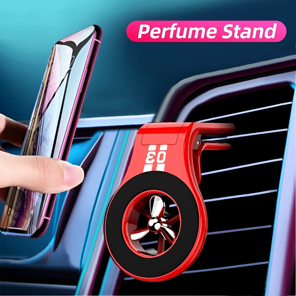 Black magnetic car phone holder clipped to a car air vent, holding a mobile phone, with a fragrant slice inserted.