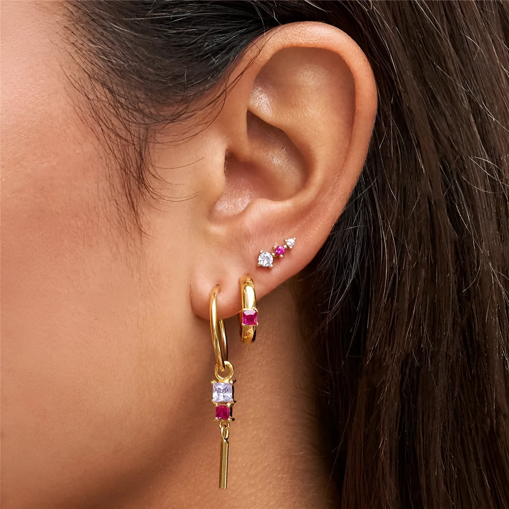 Set of three copper geometric earrings with zircon inlay on a neutral background