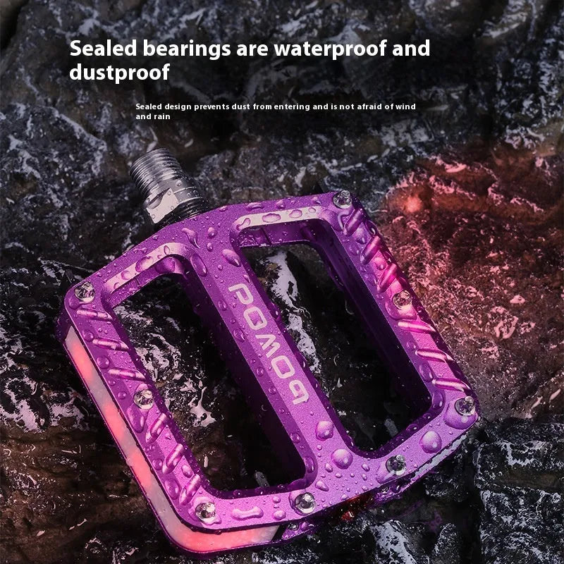 Aluminium alloy bicycle pedals with glowing 710 LED lights in purple, black, red, gold, and titanium colour options.