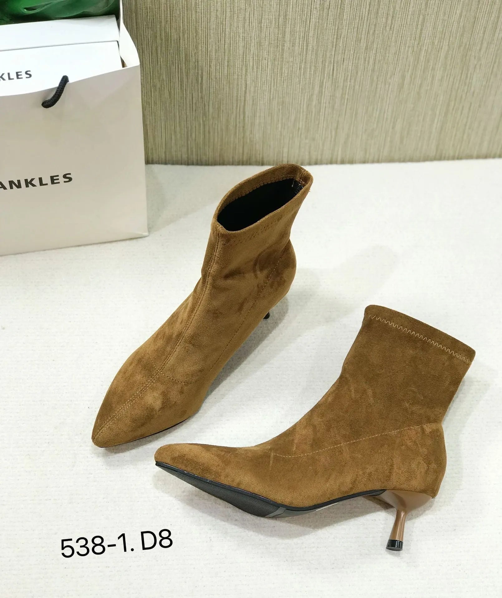Black pointed toe women's ankle boots with a stiletto heel on a plain background.