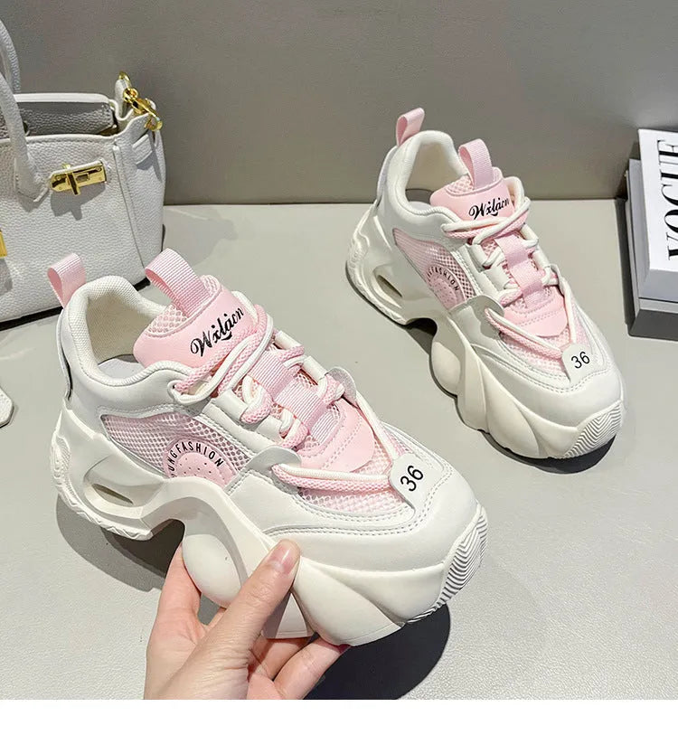 Women's pink platform sneakers with a thick sole and cross ankle straps on a white background.