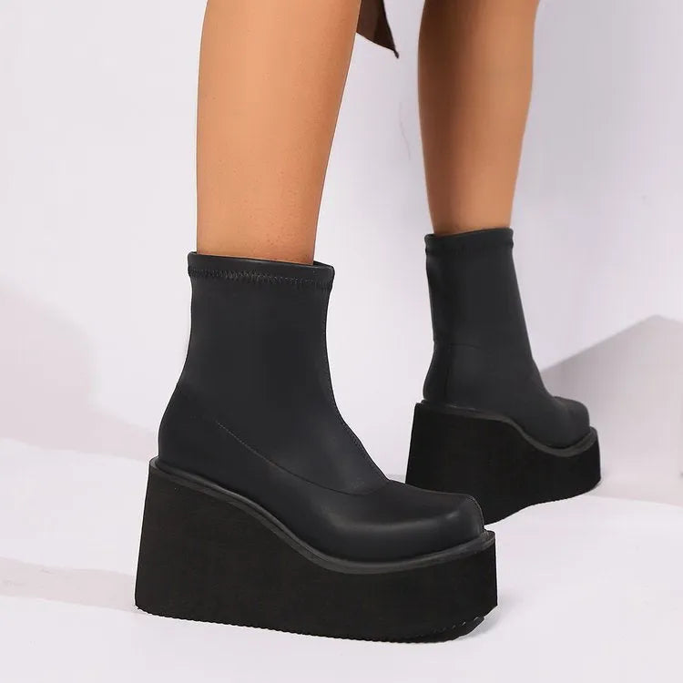 Plus size black artificial PU women's ankle boots with a wedge heel and round toe on a model.