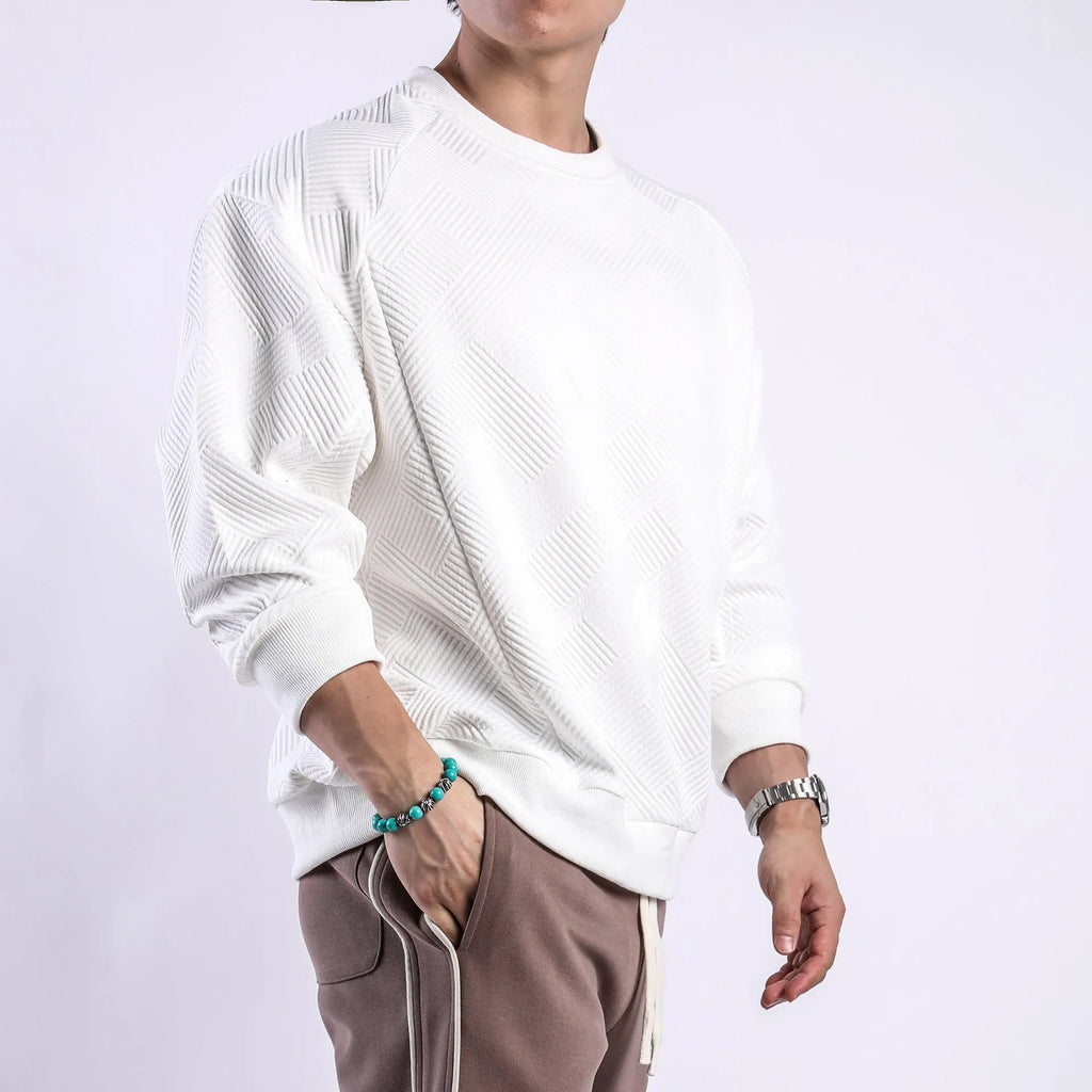 Man wearing a loose-fit, solid-colour twill jacquard long-sleeved sweater with a round neck.