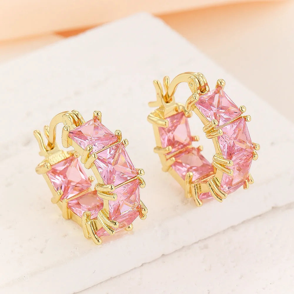 Geometric U-shaped gold earring with a round black zirconium stone on a copper base.