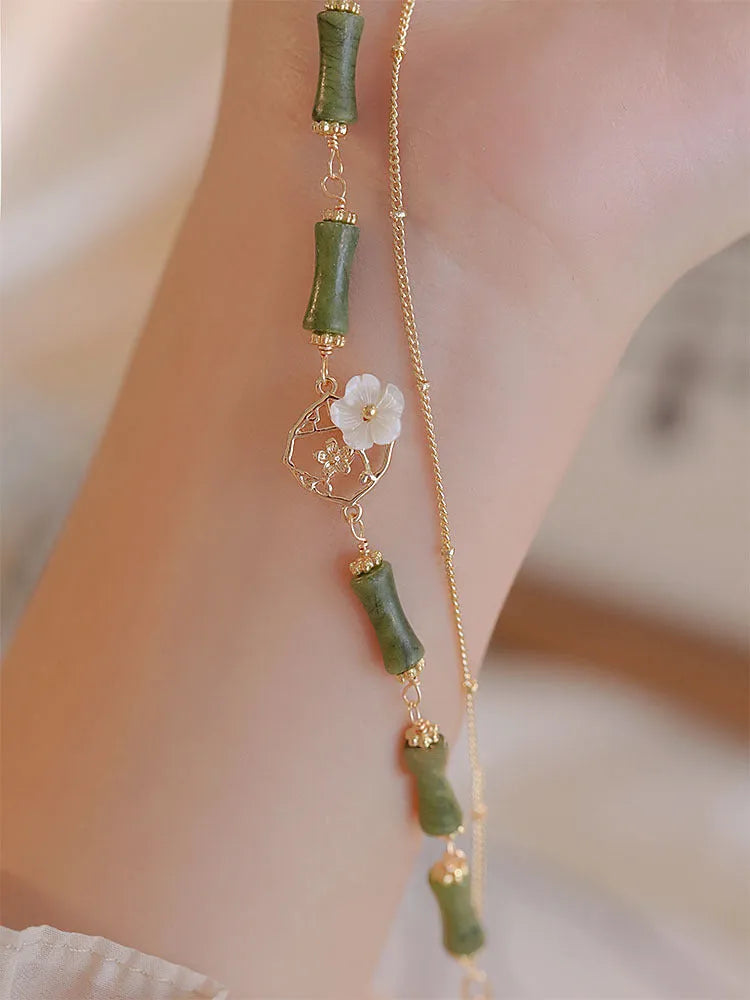 Handmade natural olivine bracelet with double layer design and Bells of Ireland charms on a wrist.