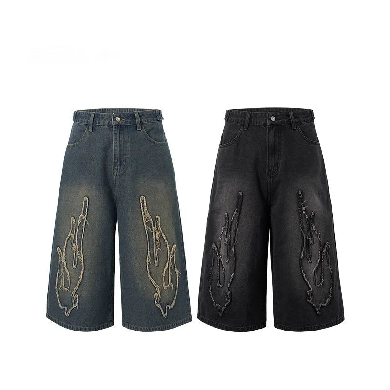Men's black denim shorts with a cropped flame embroidery patch on the leg