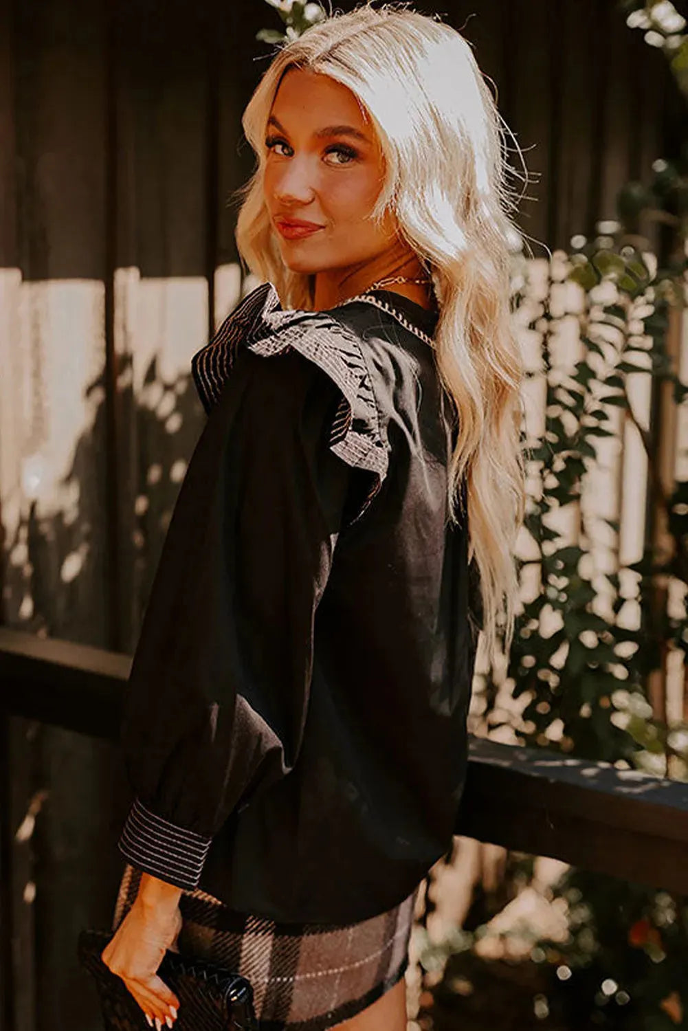 Black V-neck blouse with contrast stitching on ruffle long sleeves