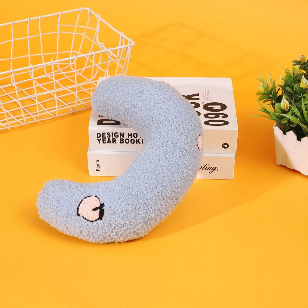 Blue U-shaped half moon cartoon pillow for cats on a wooden floor.