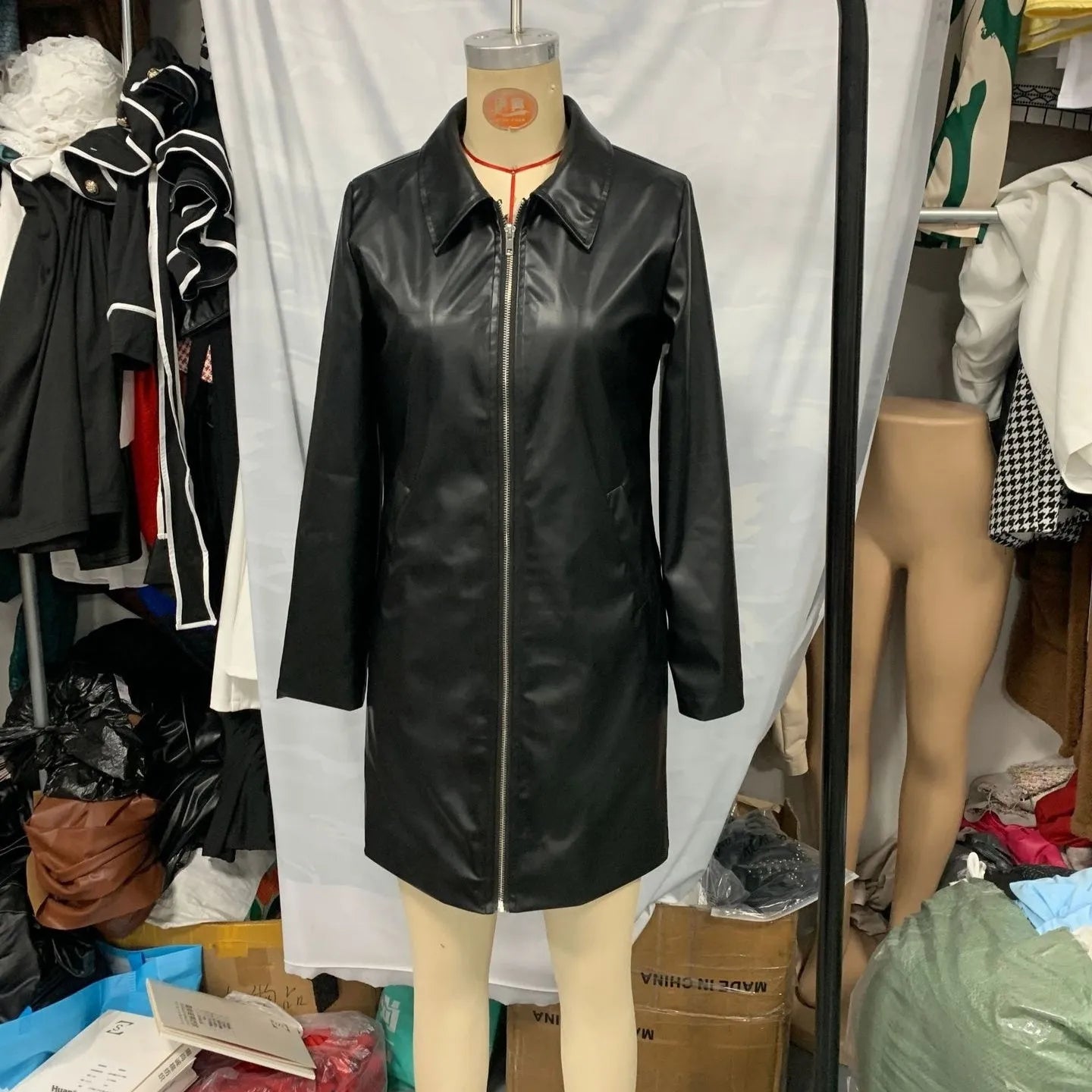 Black mid-length polyester leather jacket for women on a hanger.