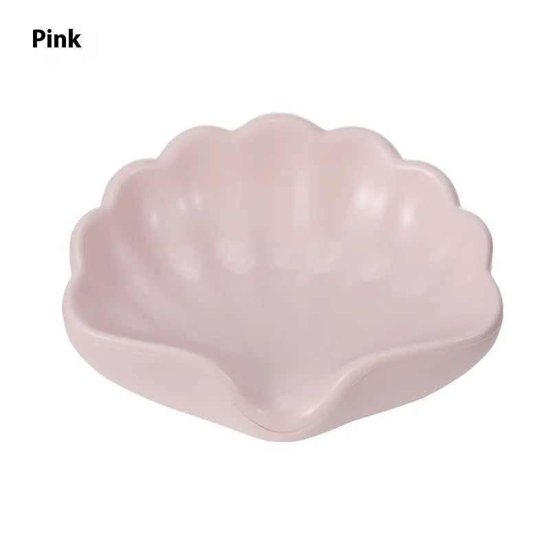 White plastic shell-shaped soap dish for bathroom countertop with soap bar on it.
