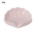 White plastic shell-shaped soap dish for bathroom countertop with soap bar on it.