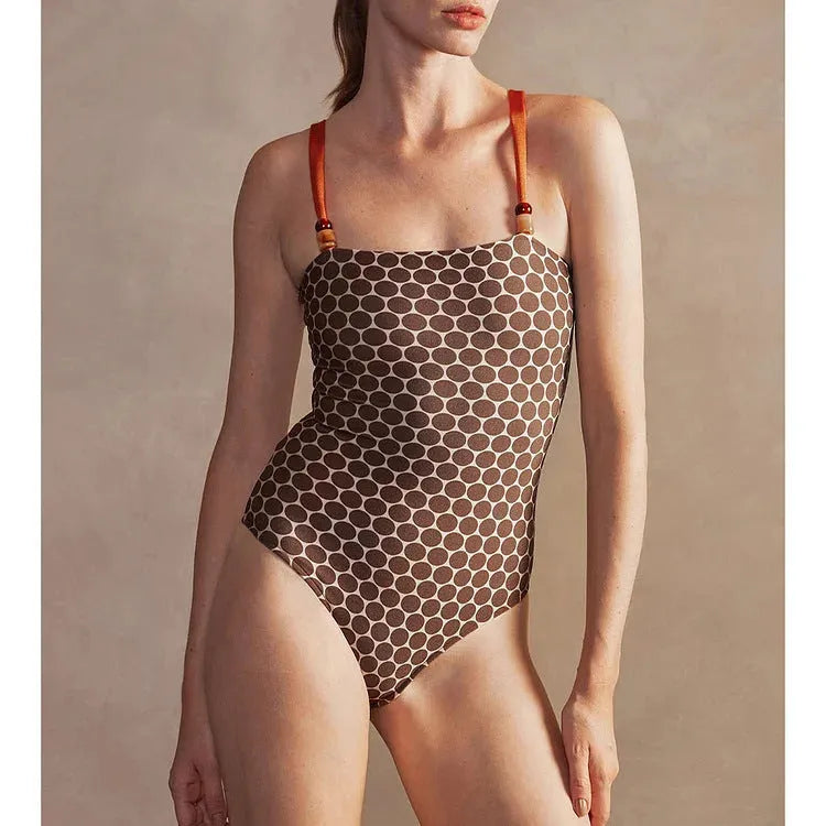 Women's dot-pattern one-piece swimsuit with matching wrap skirt set on a hanger.