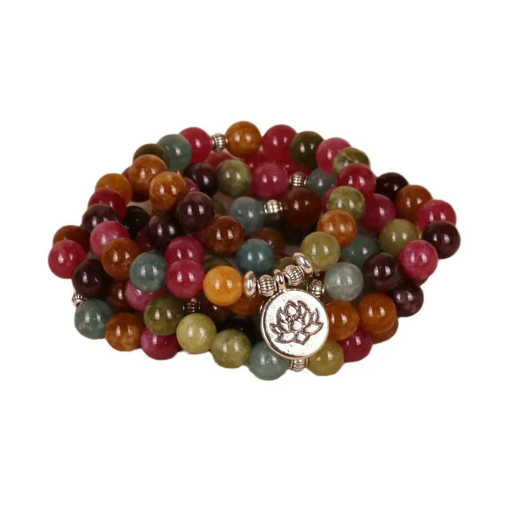 Multi-layer beaded bracelet with 108 tourmaline beads, lotus charm, and alloy clasp on a wrist.