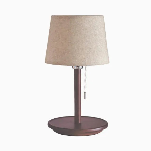 Walnut colour solid wood bedside lamp with a white fabric lampshade and a black cable switch.
