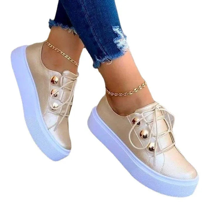 Women's white lace-up flats sneakers with decorative silver rivets and front-tie lacing.