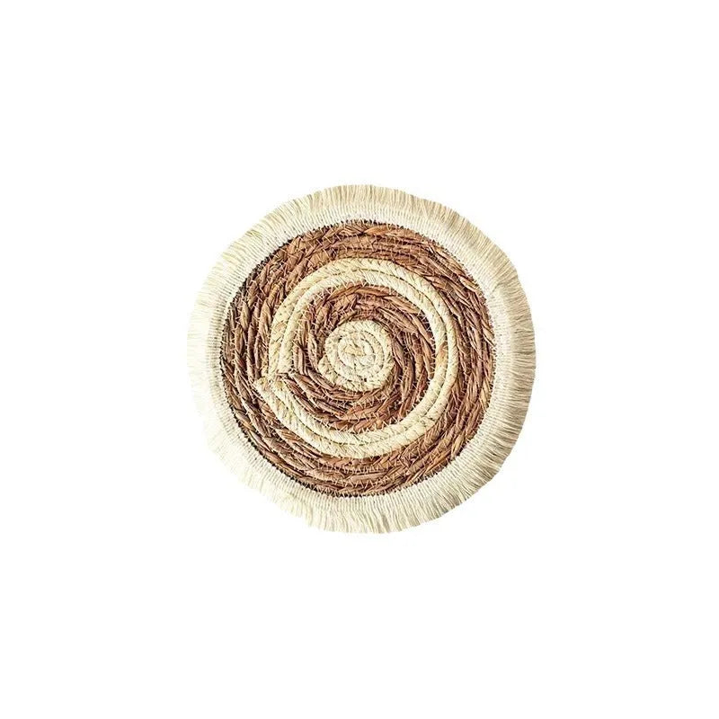 Round natural papyrus straw placemat with decorative tassel edge on a wooden table.