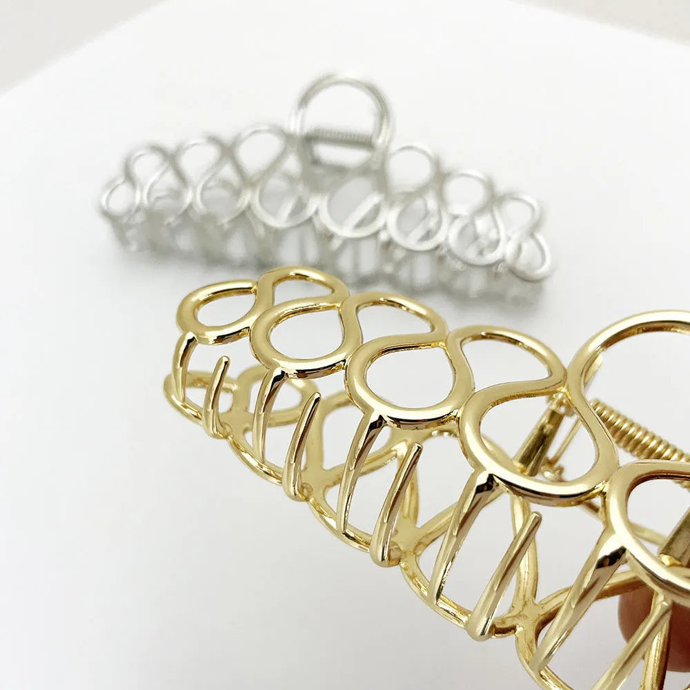 Large gold and silver alloy hair clip with a tassel detail on a white background.
