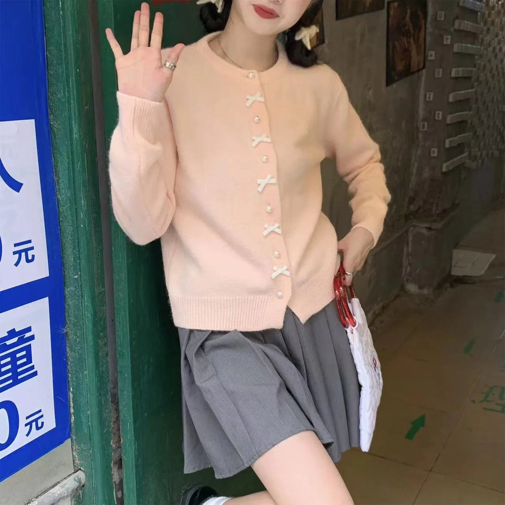 Women's solid colour cardigan with a bow and pearl buttons, shown in a light colour.