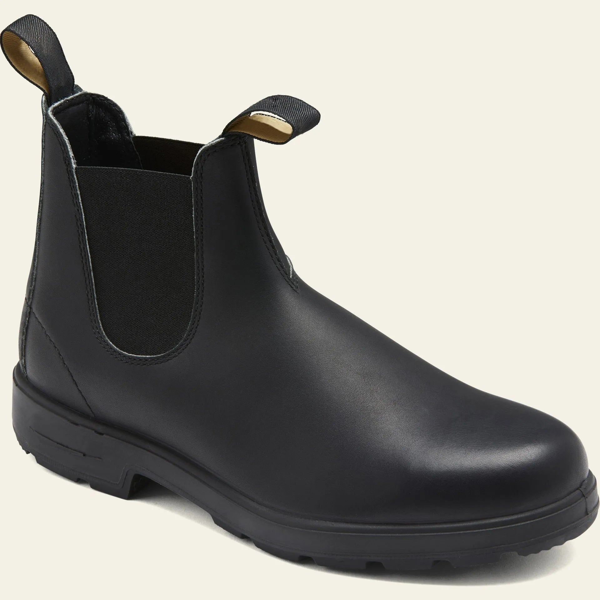 Vintage brown Chelsea boots with frosted finish and car suture detailing on a wooden floor.
