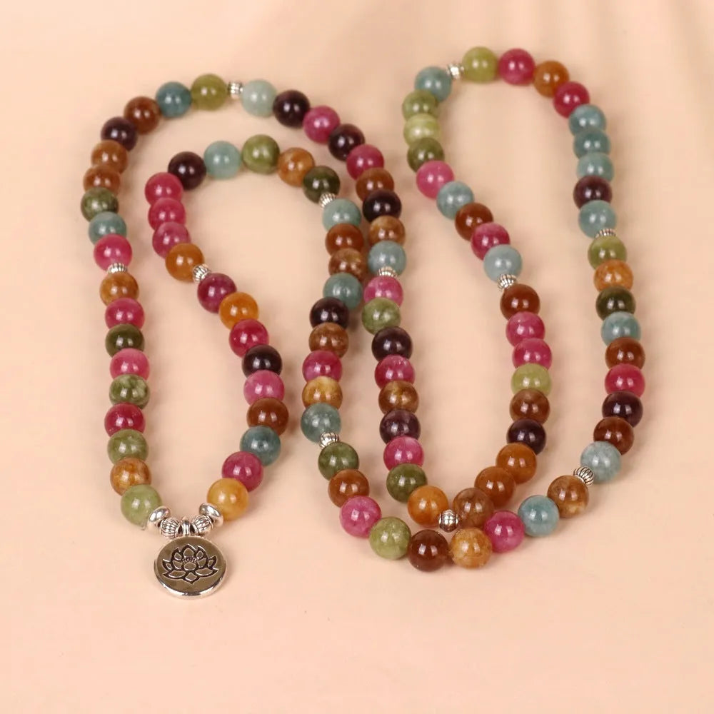 Multi-layer beaded bracelet with 108 tourmaline beads, lotus charm, and alloy clasp on a wrist.