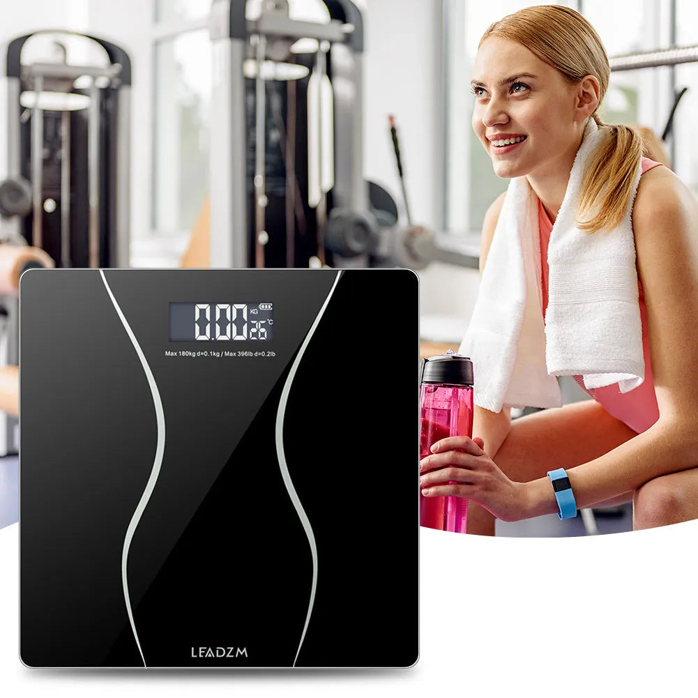 Black electronic digital bathroom scale with LCD display on a bathroom floor.