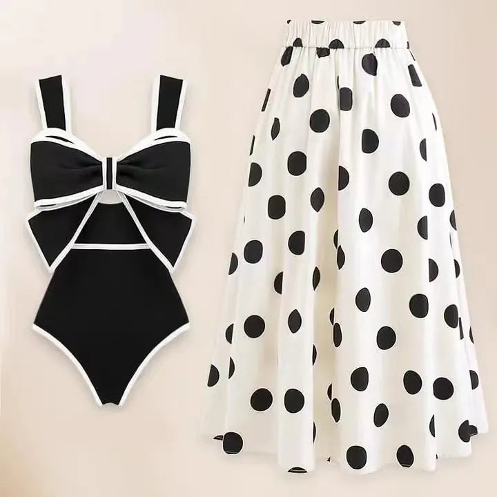 Women's black one-piece swimsuit with attached beach dress skirt featuring bow detail