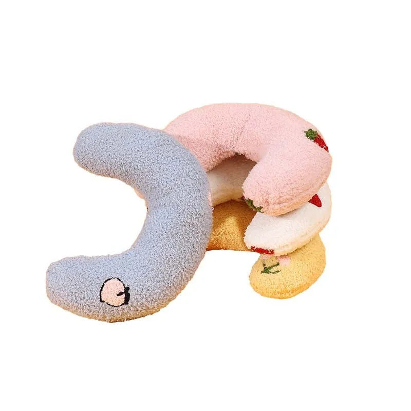 Blue U-shaped half moon cartoon pillow for cats on a wooden floor.