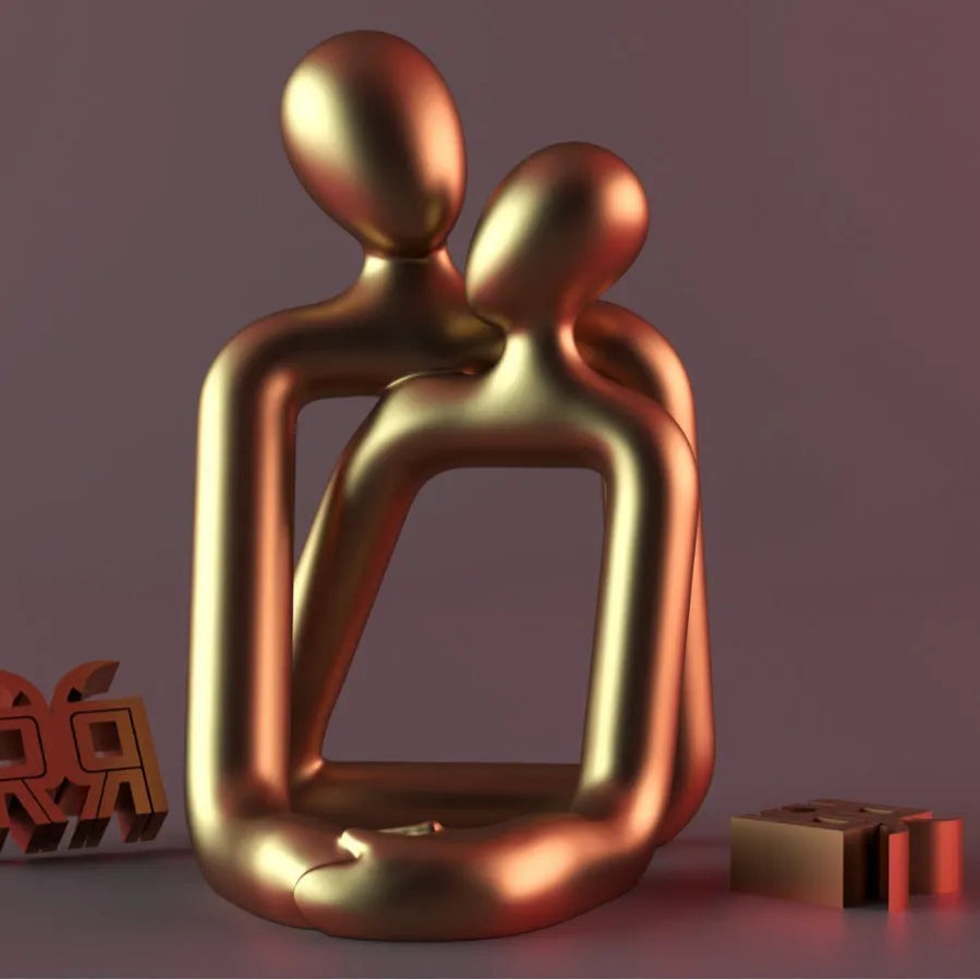 Modern loving couple resin statue in gold or milky white finish on a wooden desk.