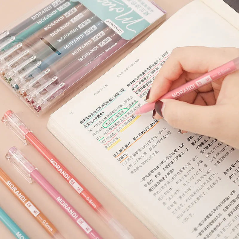 Set of nine colourful retro gel pens with 0.5mm needle tips, shown alongside a notebook.