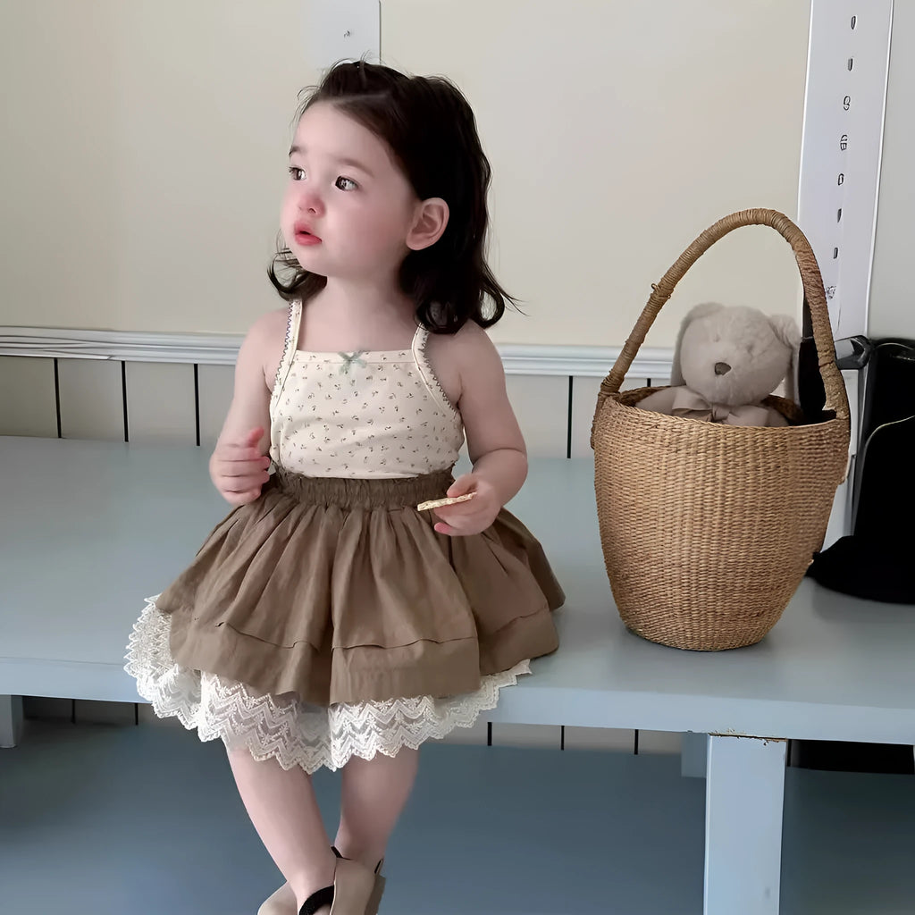 Baby girl wearing floral camisole vest and brown cotton skirt with dots pattern on a white background
