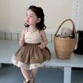Baby girl wearing floral camisole vest and brown cotton skirt with dots pattern on a white background