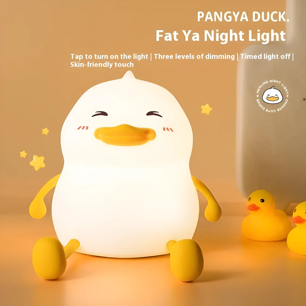 Chubby silicone and plastic night light on desk holding a mobile phone with soft LED glow.
