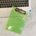 Transparent A4 writing board pad with metal clip holding documents, available in blue, green, red, and white colours