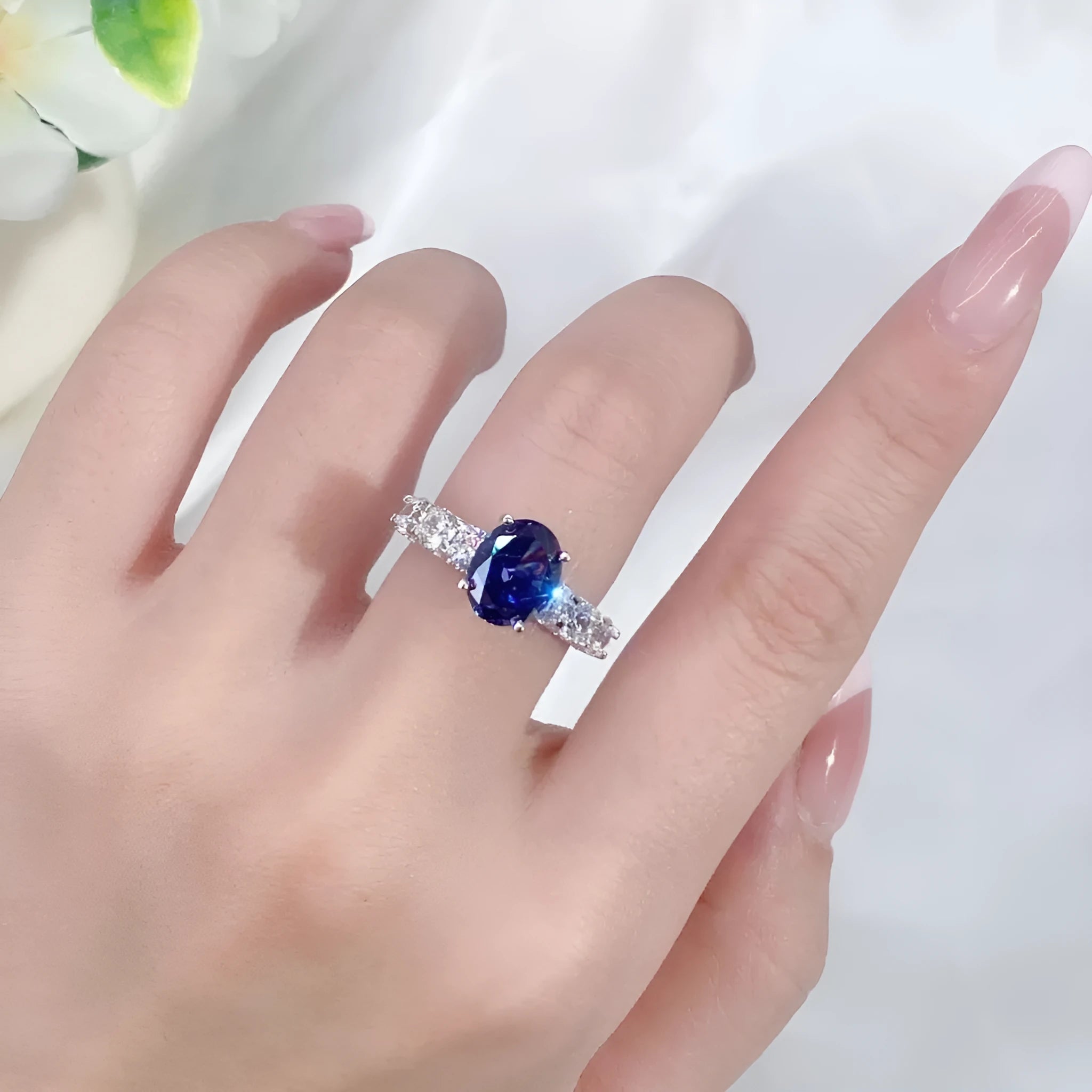 Heart-shaped 925 sterling silver ring with a sparkling ice flower cut colour zircon stone on a finger.