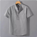 Men's loose-fit solid colour linen shirt with a stand collar and short sleeves on a hanger.