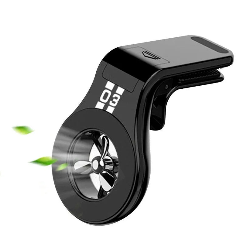Black magnetic car phone holder clipped to a car air vent, holding a mobile phone, with a fragrant slice inserted.