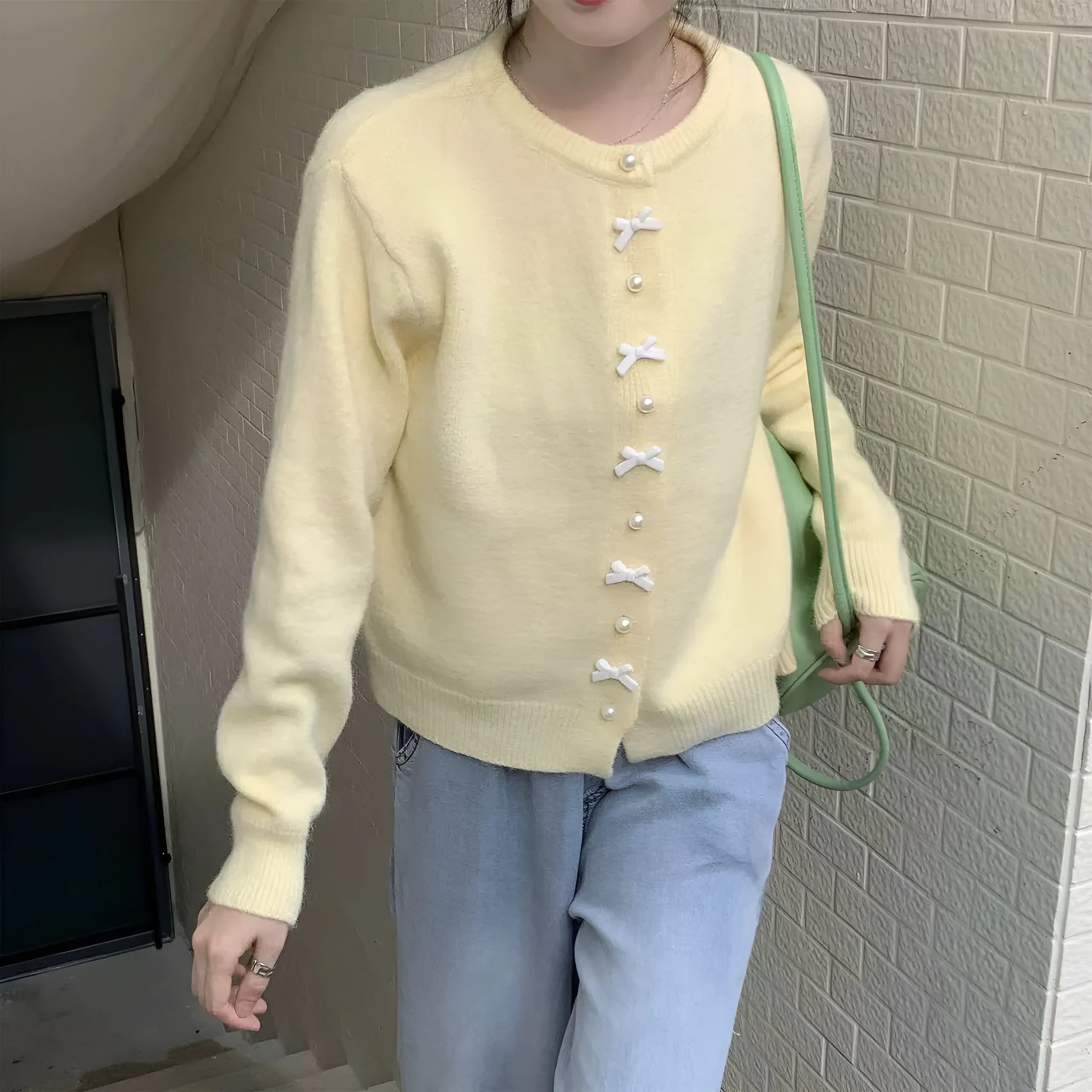 Women's solid colour cardigan with a bow and pearl buttons, shown in a light colour.