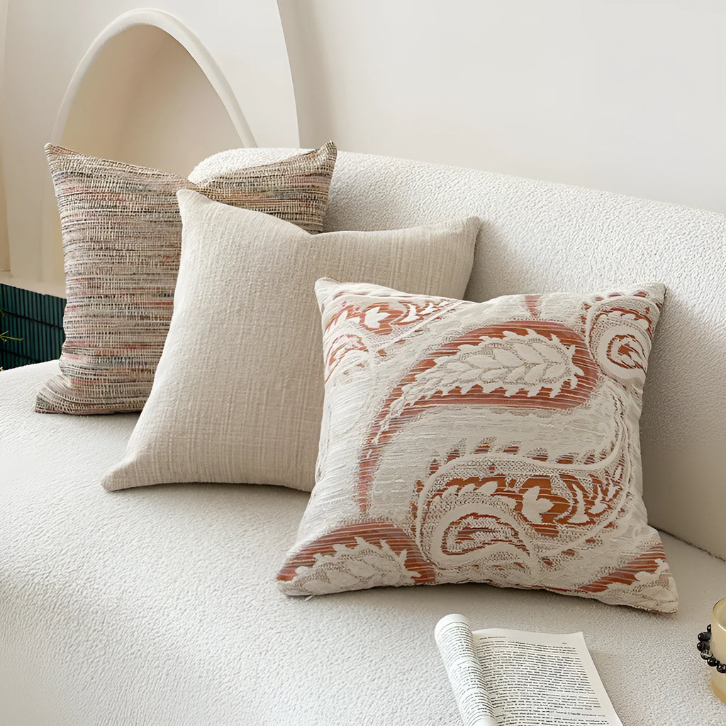 Amber jacquard paisley pillow cover on a sofa, showing textured fabric and botanical pattern.