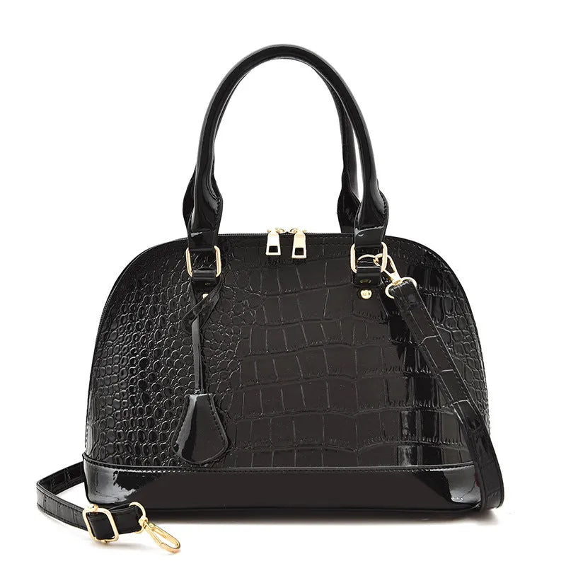 Large shiny black crossbody shoulder bag showing structured shell shape and dimensions