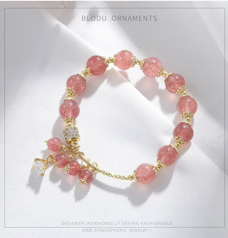 Pink heart-shaped strawberry quartz and pearl women's bracelet on a wrist.