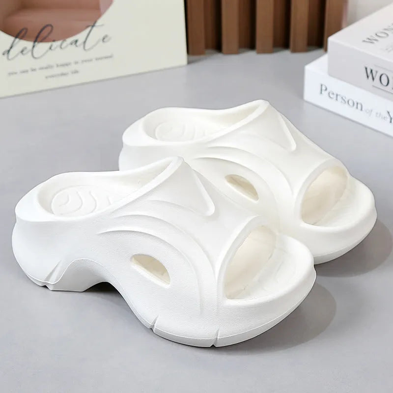 Women's white thick-soled EVA beach slippers with round toe, shown on a sandy background.