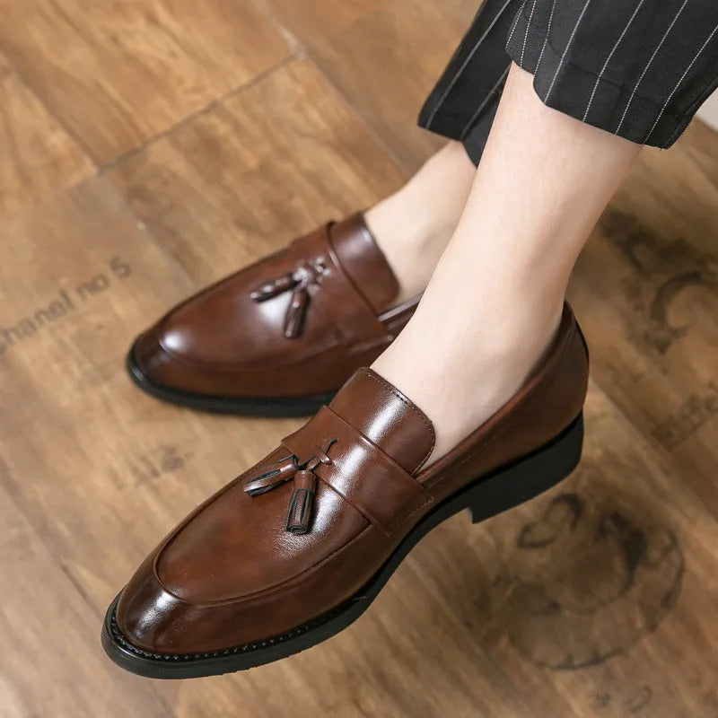 Men's black slip-on business casual shoes with a tassel detail and pointed toe.