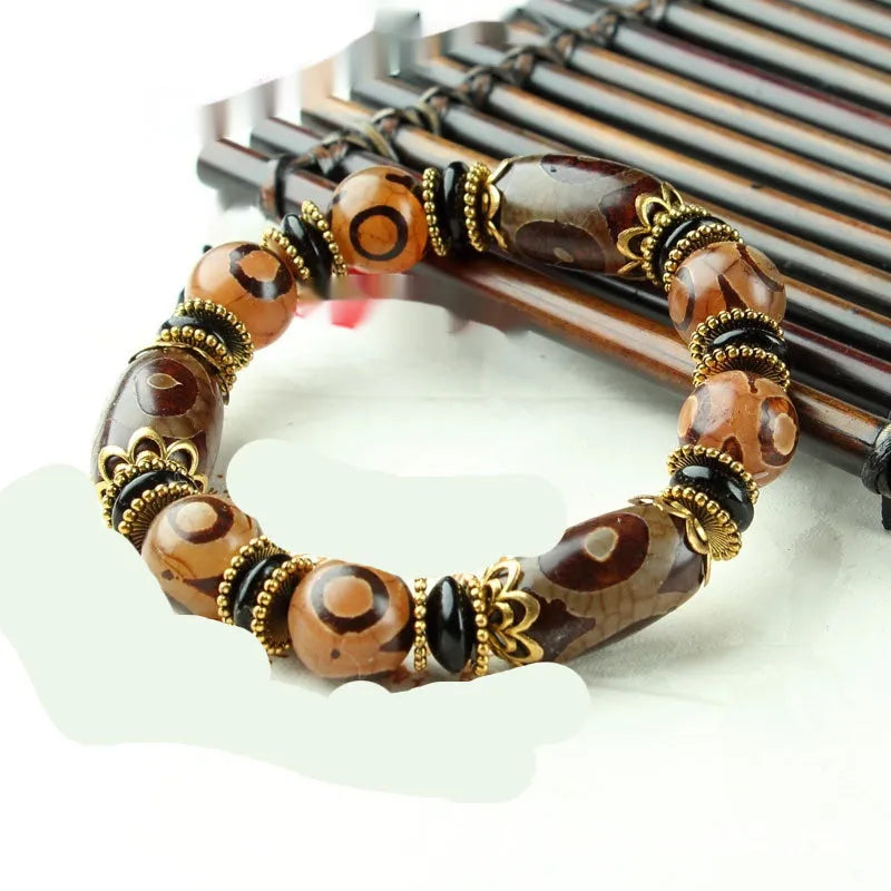 Distressed agate Tibet bead bracelet with three-eye motifs and multiple traditional bead styles on wrist