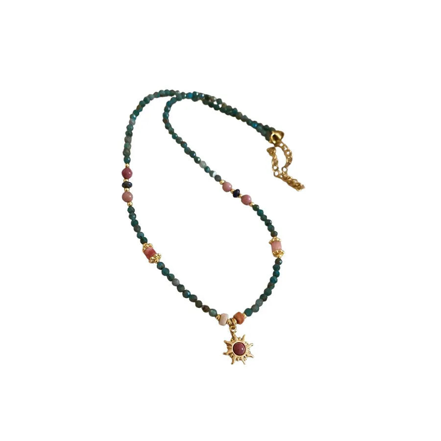 French royal style sun necklace with stone pendant and freshwater pearls on a gold and blue chain.