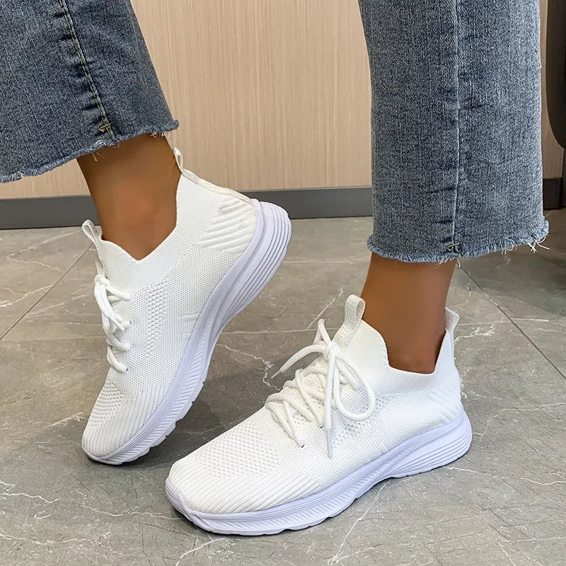 Women's Flyknit mesh running shoes in creamy white colour showing low-top slip-on design and rubber sole.