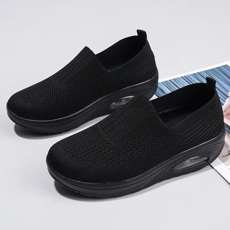Women's black mesh running shoes with air cushion midsole and round toe on a grey background.